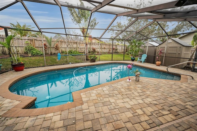 view of pool featuring a patio, glass enclosure, and a storage shed