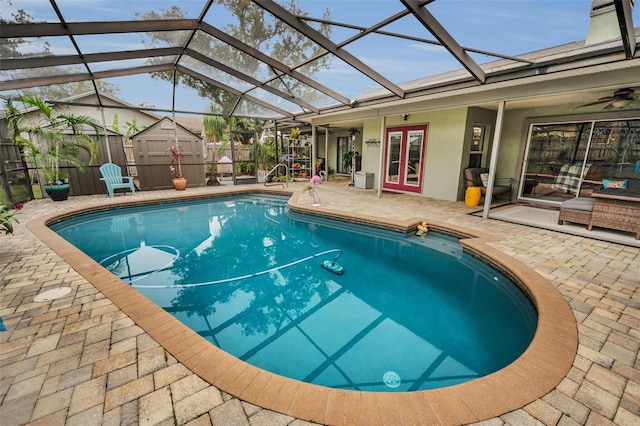 view of swimming pool with a patio, glass enclosure, and a storage shed