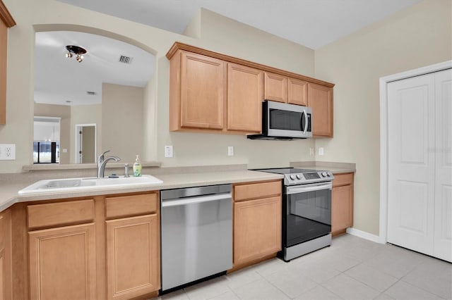 kitchen featuring stainless steel appliances, light brown cabinetry, sink, and light tile patterned floors