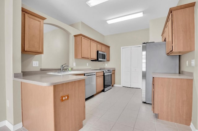 kitchen with appliances with stainless steel finishes, light brown cabinetry, sink, light tile patterned floors, and kitchen peninsula