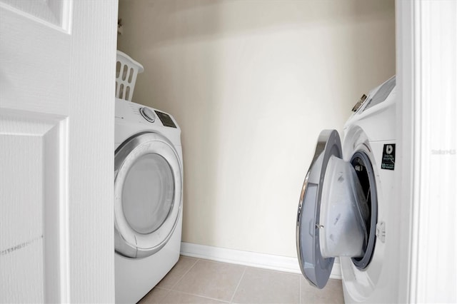 clothes washing area featuring washing machine and dryer and light tile patterned floors