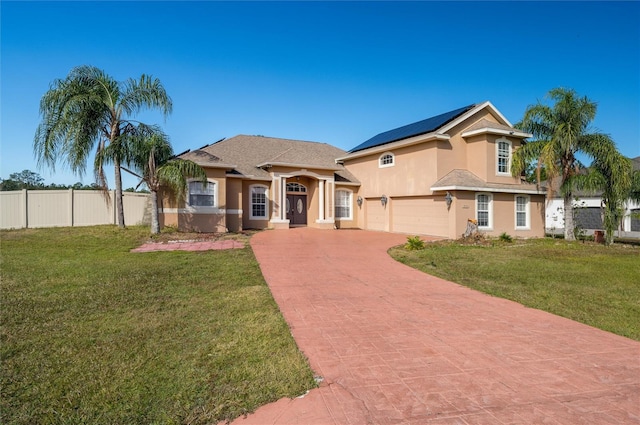 view of front of home featuring a garage, a front lawn, and solar panels