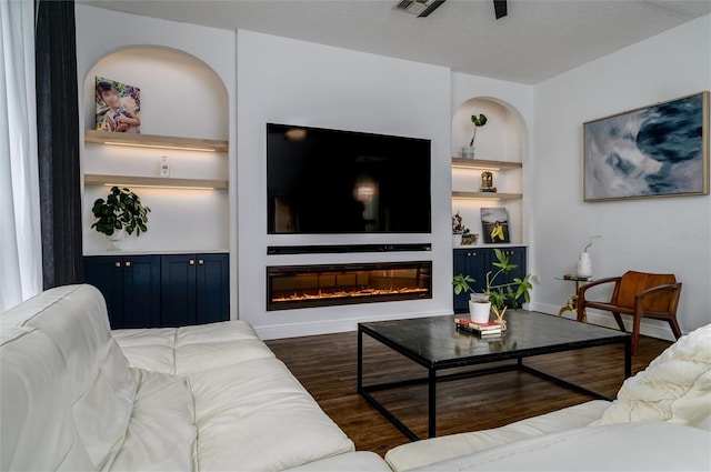 living room with built in shelves and dark hardwood / wood-style flooring