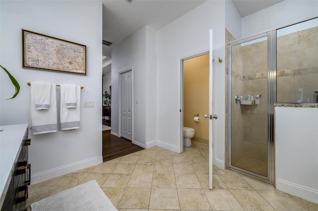 bathroom with walk in shower, vanity, toilet, and tile patterned flooring