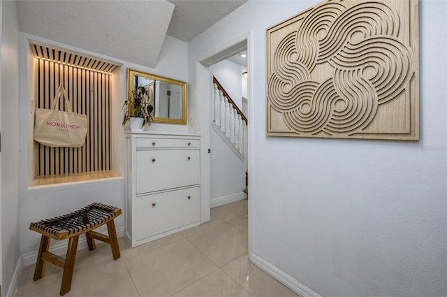 mudroom featuring a textured ceiling and light tile patterned floors