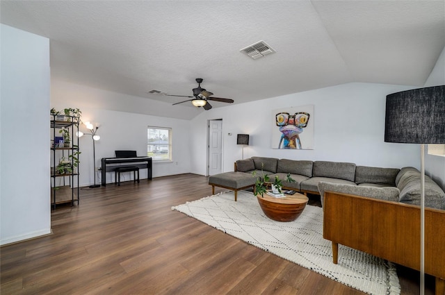 living room featuring ceiling fan, lofted ceiling, dark wood-type flooring, and a textured ceiling