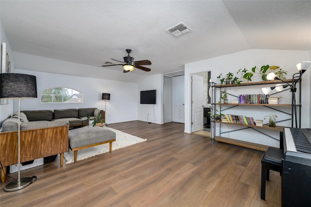 living room with vaulted ceiling, ceiling fan, a textured ceiling, and dark hardwood / wood-style flooring