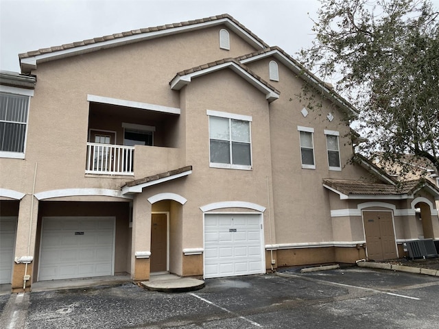 view of front of home featuring cooling unit, a balcony, and a garage