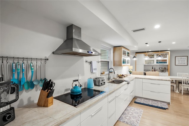 kitchen with island range hood, white cabinetry, sink, black electric stovetop, and light hardwood / wood-style flooring