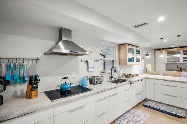 kitchen with sink, white cabinetry, decorative light fixtures, black electric cooktop, and exhaust hood