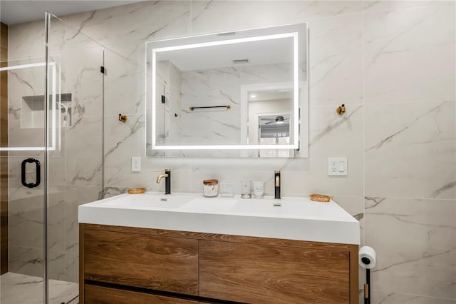 bathroom featuring walk in shower, vanity, and tile walls