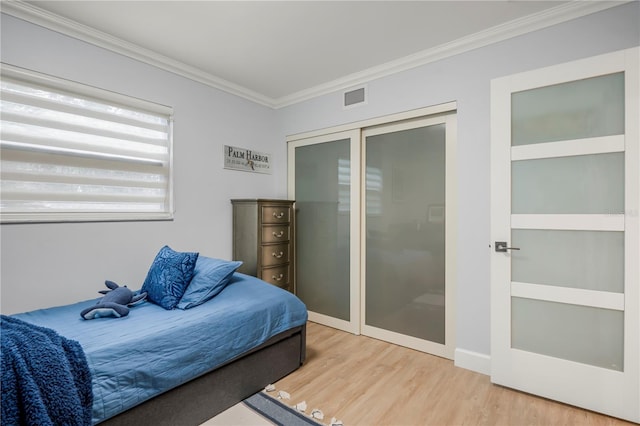 bedroom with hardwood / wood-style flooring, ornamental molding, and a closet