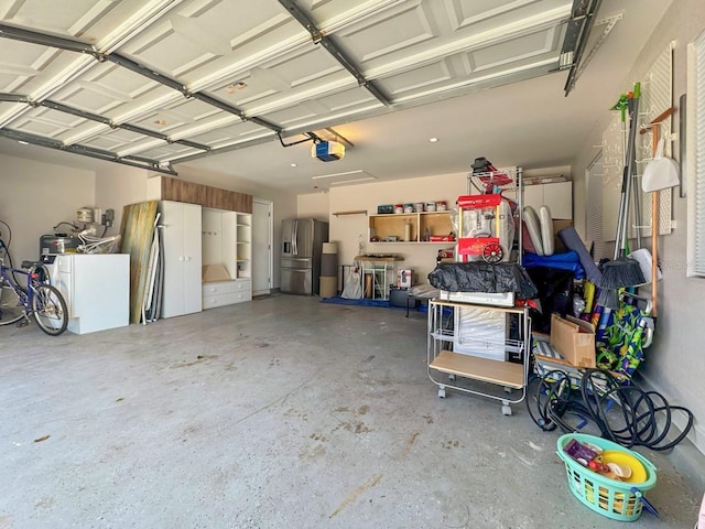 garage with a garage door opener and stainless steel fridge