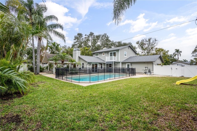 back of property featuring a balcony, a fenced in pool, a patio, and a lawn