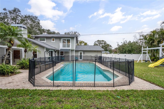 view of swimming pool with a playground and a lawn