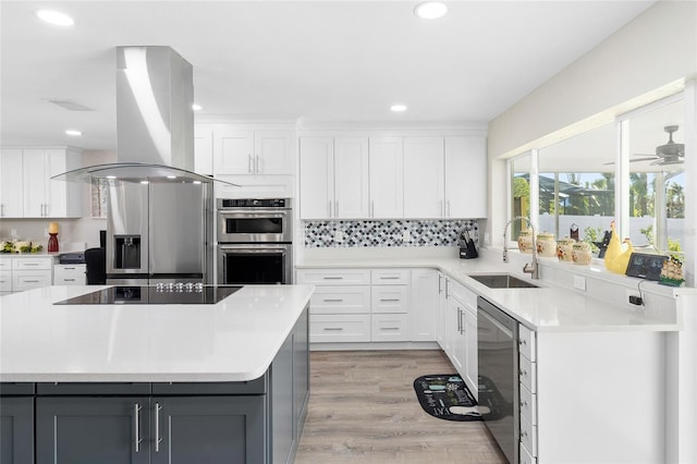 kitchen featuring sink, a center island, appliances with stainless steel finishes, island exhaust hood, and white cabinets