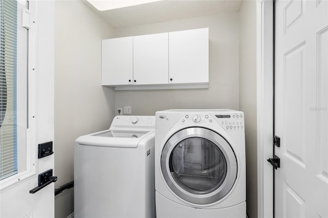 laundry room featuring cabinets, separate washer and dryer, and a textured ceiling