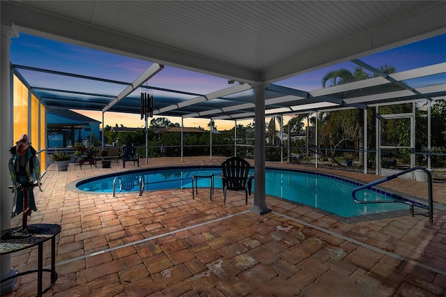 pool at dusk featuring a lanai and a patio area