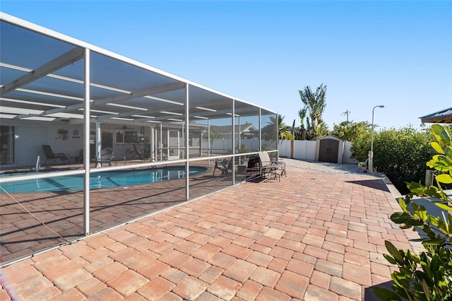 view of pool featuring a storage unit, a patio, and glass enclosure