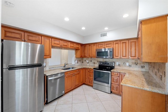 kitchen with tasteful backsplash, sink, light tile patterned floors, light stone counters, and stainless steel appliances