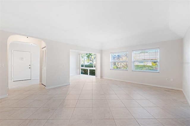 tiled empty room featuring a raised ceiling