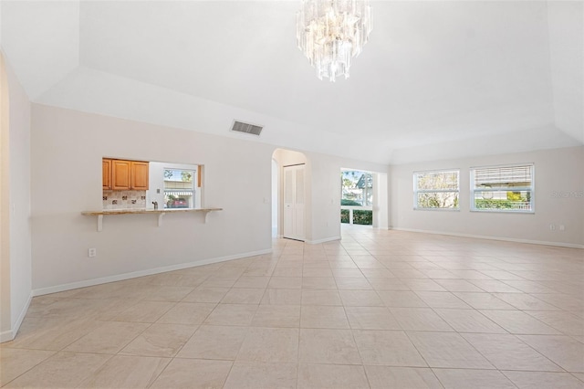 unfurnished living room featuring a raised ceiling, light tile patterned flooring, and a notable chandelier