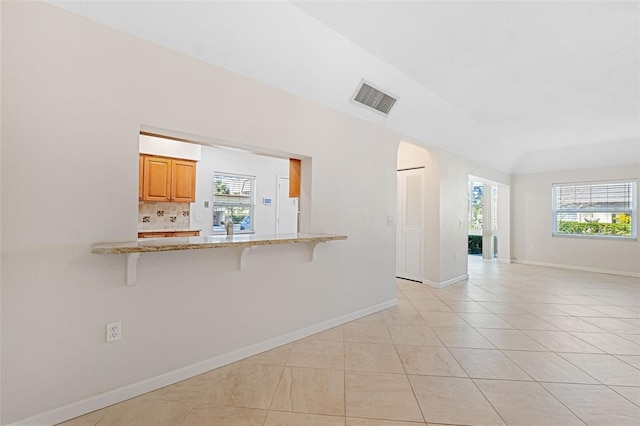 unfurnished living room featuring light tile patterned flooring and vaulted ceiling