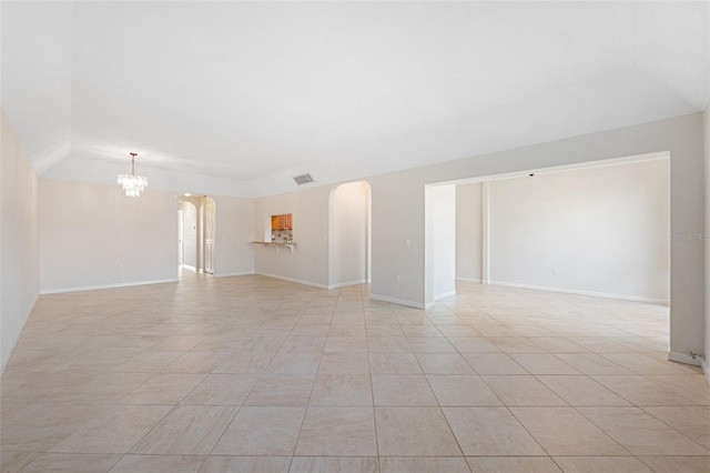 tiled spare room with an inviting chandelier and vaulted ceiling