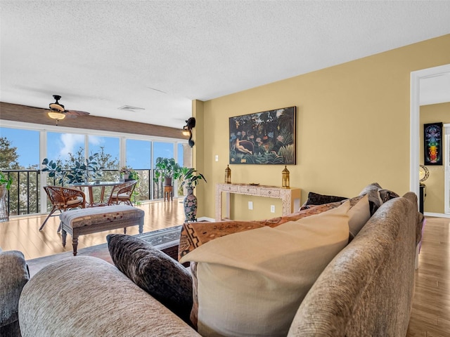 living room with baseboards, visible vents, a ceiling fan, wood finished floors, and a textured ceiling