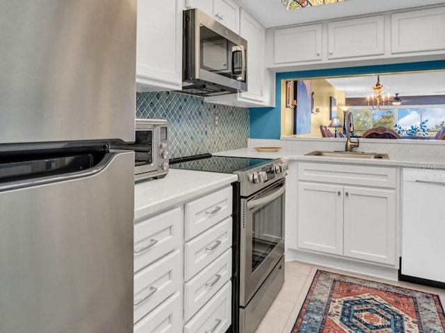 kitchen with stainless steel appliances, tasteful backsplash, light countertops, white cabinetry, and a sink