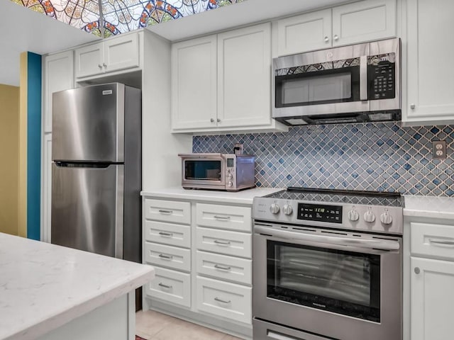 kitchen featuring appliances with stainless steel finishes, a toaster, white cabinets, and backsplash