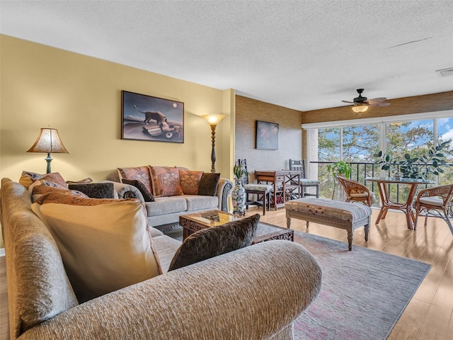 living room with visible vents, a textured ceiling, a ceiling fan, and wood finished floors