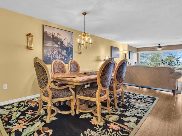 dining space with an inviting chandelier, a textured ceiling, baseboards, and hardwood / wood-style floors