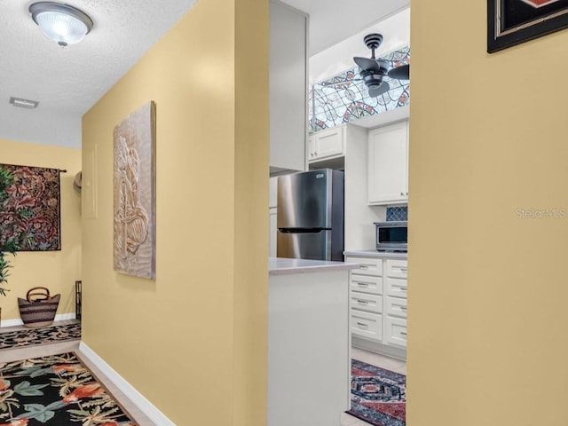 hall with a textured ceiling and baseboards