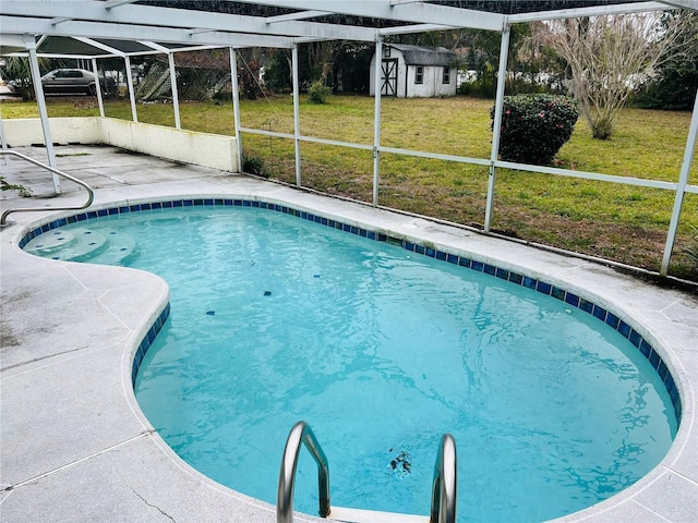 view of swimming pool featuring a patio area, a lawn, glass enclosure, and a storage unit