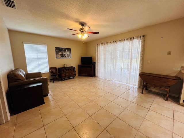 living room featuring ceiling fan, a wealth of natural light, a textured ceiling, and light tile patterned flooring