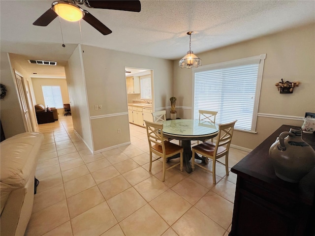 dining area with sink, plenty of natural light, a textured ceiling, and light tile patterned flooring