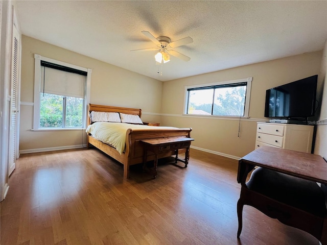 bedroom featuring ceiling fan, a closet, a textured ceiling, and light wood-type flooring