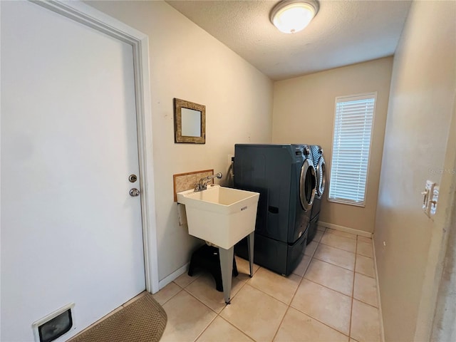 laundry area with washer and clothes dryer, a textured ceiling, and light tile patterned floors