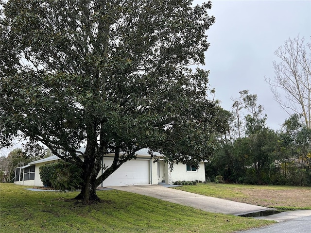 view of property hidden behind natural elements with a garage and a front lawn