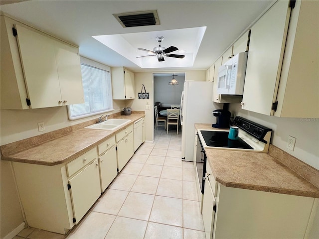 kitchen featuring sink, white appliances, light tile patterned floors, a tray ceiling, and ceiling fan