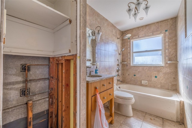 full bathroom with tiled shower / bath, vanity, toilet, and tile walls