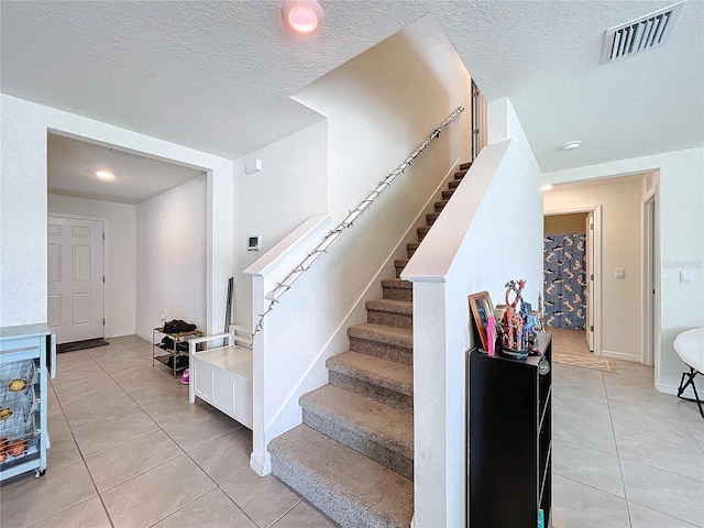 stairs featuring tile patterned flooring and a textured ceiling