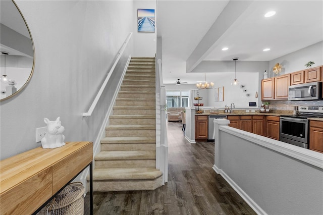 kitchen with dark wood-type flooring, sink, kitchen peninsula, pendant lighting, and stainless steel appliances