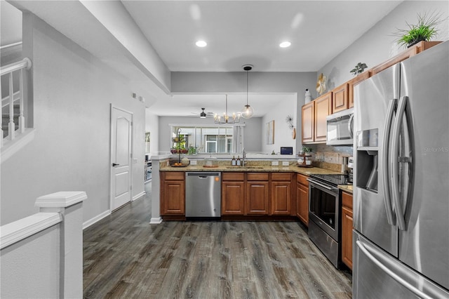 kitchen with pendant lighting, stainless steel appliances, kitchen peninsula, and sink