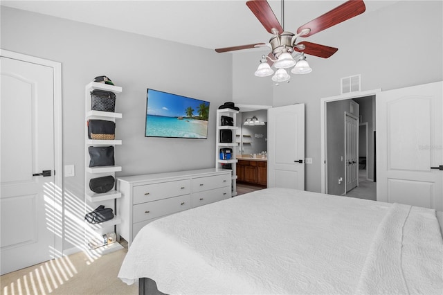 bedroom with high vaulted ceiling, light carpet, connected bathroom, and ceiling fan