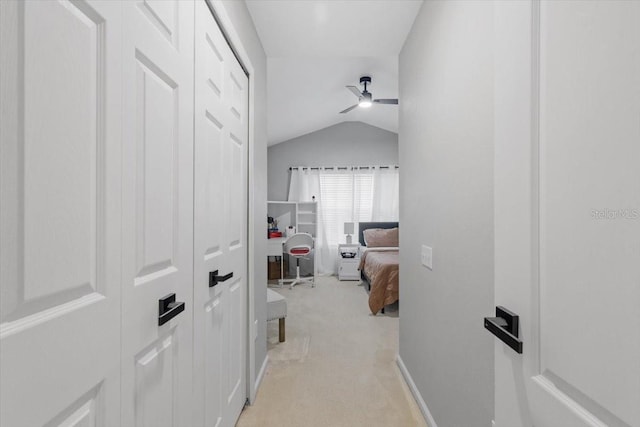 hall with lofted ceiling and light carpet