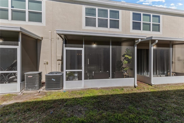 rear view of property featuring a sunroom, central AC unit, and a lawn