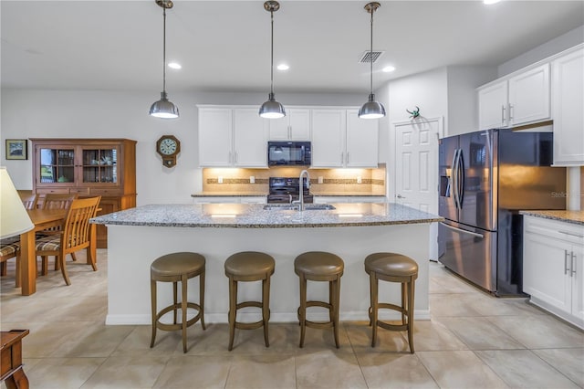 kitchen featuring a center island with sink, sink, pendant lighting, and stainless steel fridge