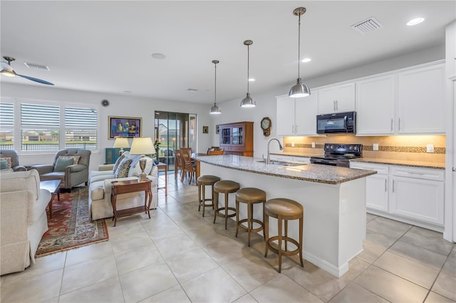 kitchen with sink, white cabinetry, pendant lighting, a kitchen island with sink, and black appliances